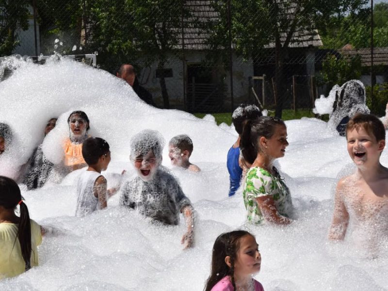 Children having fun in a foam party outdoors during summer.